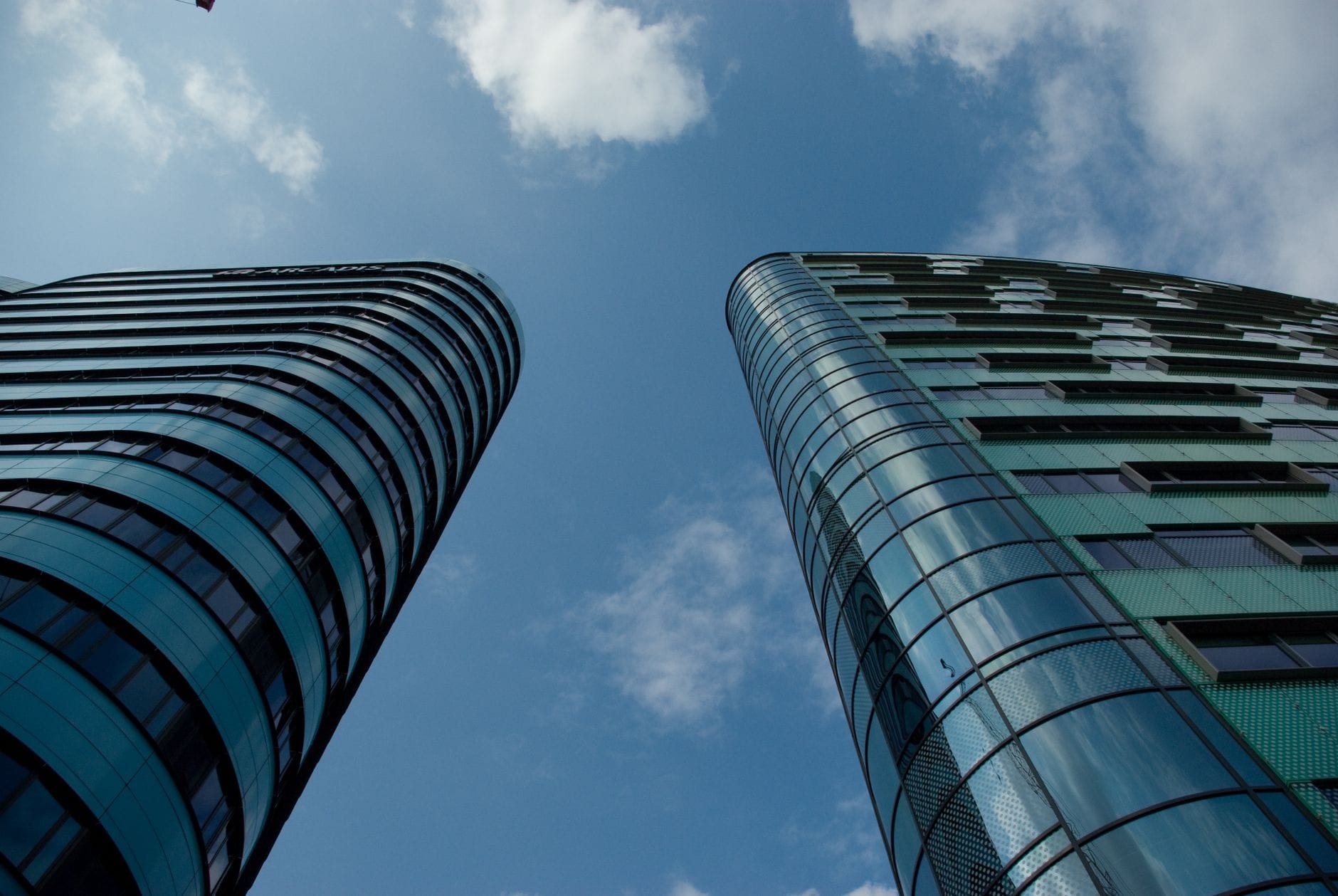 Low angle view of modern glass skyscrapers in an urban setting under a clear blue sky.